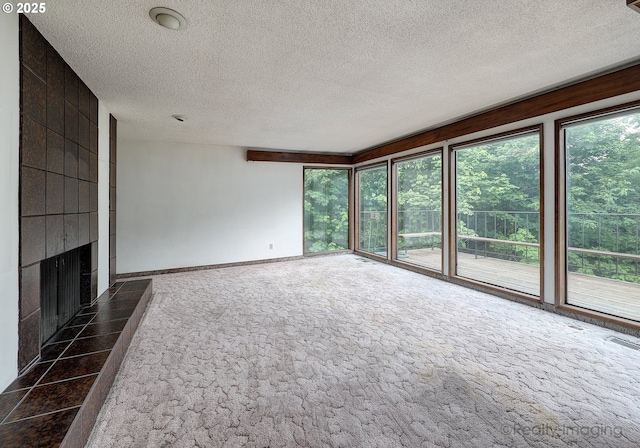 unfurnished living room featuring a textured ceiling, a tile fireplace, visible vents, and a healthy amount of sunlight