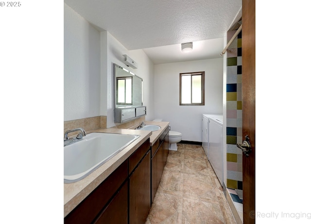 bathroom with vanity, washer and clothes dryer, toilet, and a textured ceiling