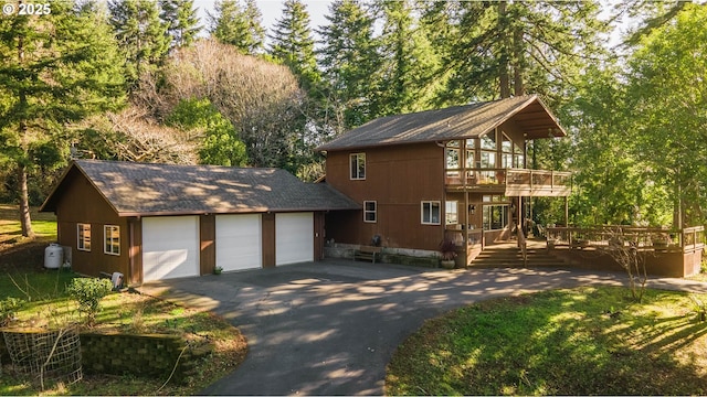 exterior space featuring a garage, a wooden deck, and an outdoor structure