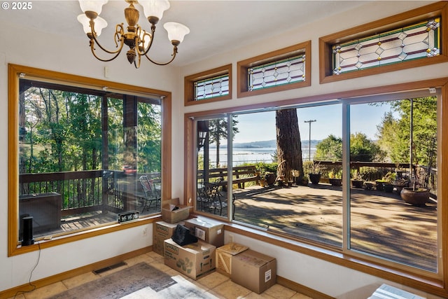 sunroom with an inviting chandelier and a water view