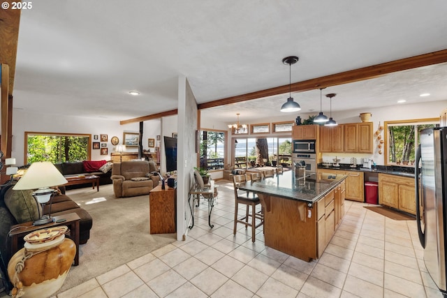 kitchen featuring light tile patterned flooring, a breakfast bar, hanging light fixtures, stainless steel appliances, and a kitchen island with sink