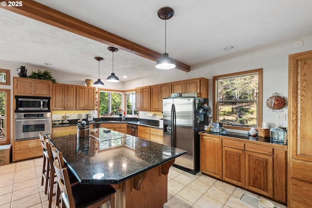 kitchen with pendant lighting, sink, a breakfast bar, stainless steel appliances, and a kitchen island