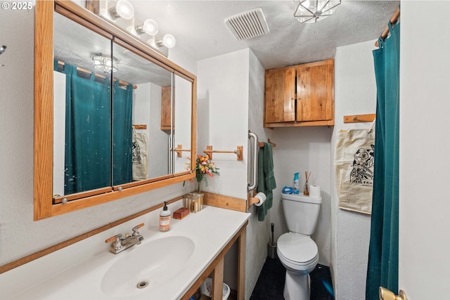 bathroom featuring vanity, a textured ceiling, and toilet