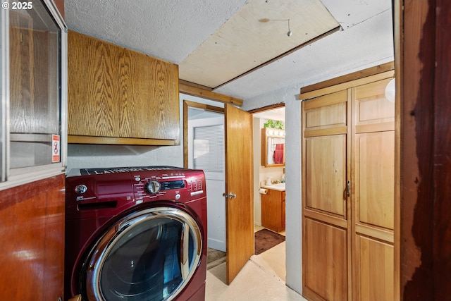 laundry area with cabinets, washer / clothes dryer, and a textured ceiling