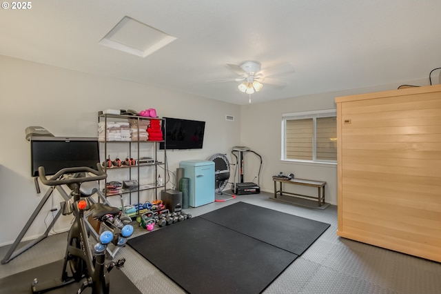 exercise room with attic access, ceiling fan, and carpet flooring