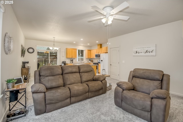 living room featuring recessed lighting, baseboards, light colored carpet, and ceiling fan with notable chandelier