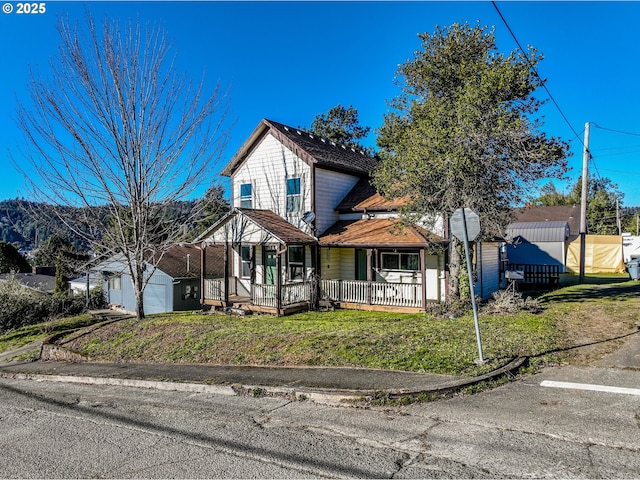 view of front of home featuring a garage, an outdoor structure, a front lawn, and a porch