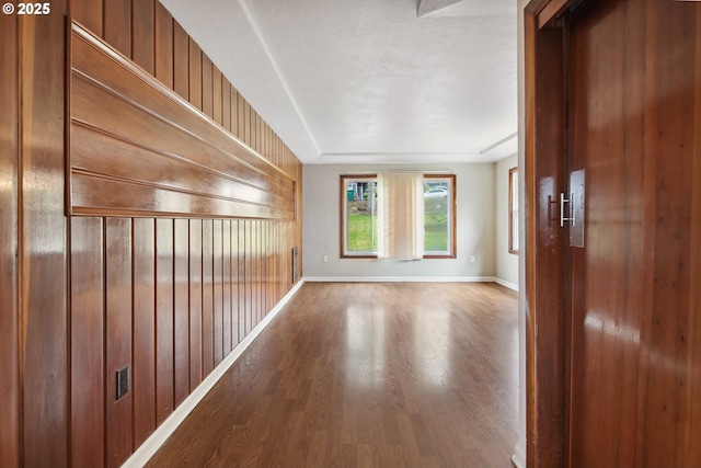 hall with baseboards, wooden walls, and wood finished floors