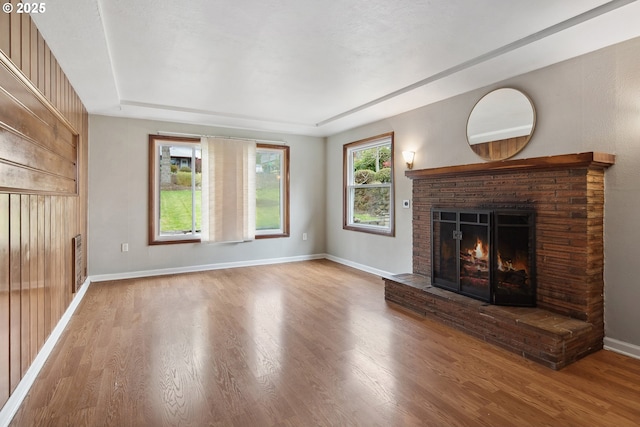 unfurnished living room featuring baseboards, a fireplace, and wood finished floors
