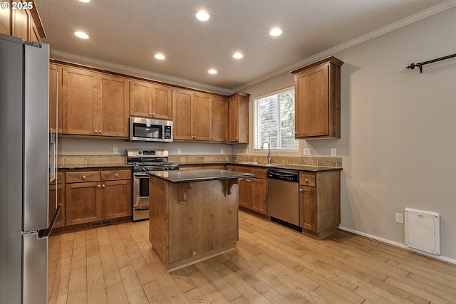 20074 SW Squire Dr, Beaverton, OR 97007 - kitchen featuring appliances with stainless steel finishes, crown molding, a breakfast bar area, light wood finished floors, and recessed lighting