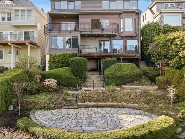rear view of property with stairs and a balcony
