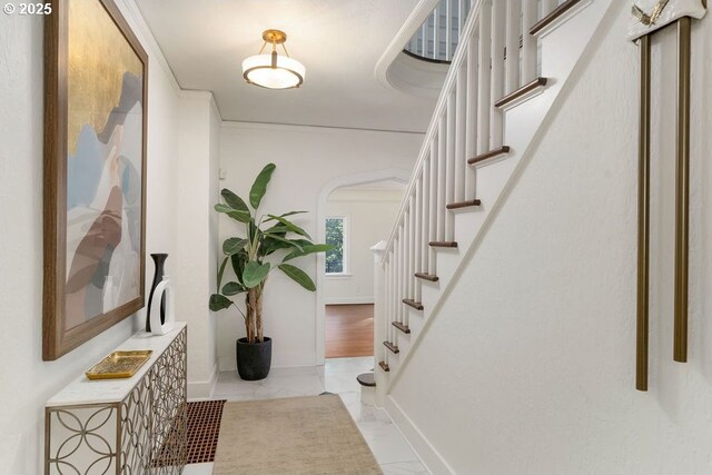 hallway featuring stairway, baseboards, and arched walkways