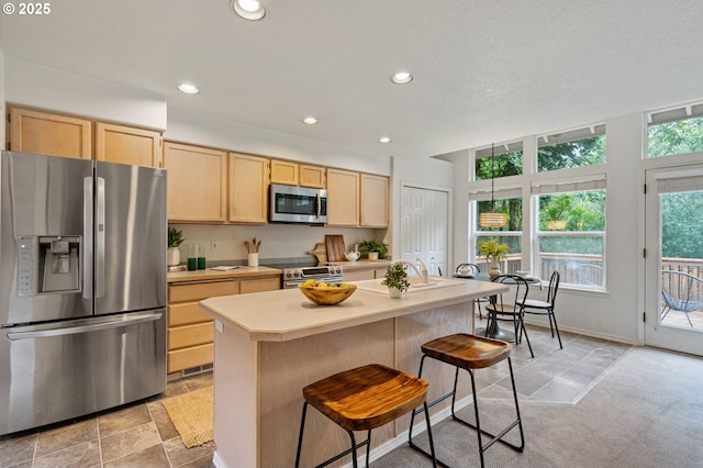 11069 SW Eschman Way, Tigard, OR 97223 - kitchen featuring stainless steel appliances, light brown cabinets, light countertops, recessed lighting, and a breakfast bar