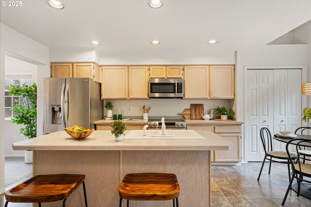11069 SW Eschman Way, Tigard, OR 97223 - kitchen with stainless steel appliances, light brown cabinets, a kitchen breakfast bar, light countertops, and recessed lighting