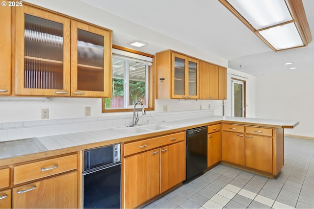 2335 5th St, Columbia City, OR 97018 - kitchen featuring black dishwasher, a peninsula, light tile patterned flooring, and glass insert cabinets