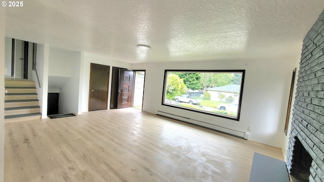 437 SE 154th Ave, Portland, OR 97233 - unfurnished living room featuring a baseboard radiator, a fireplace, wood finished floors, a textured ceiling, and stairway