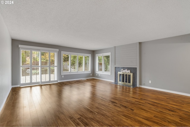 8070 SW Fairway Dr, Wilsonville, OR 97070 - unfurnished living room featuring a textured ceiling, dark wood-style flooring, a fireplace, and healthy amount of natural light