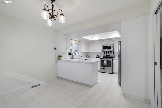 8070 SW Fairway Dr, Wilsonville, OR 97070 - kitchen with appliances with stainless steel finishes, a peninsula, a chandelier, and decorative backsplash