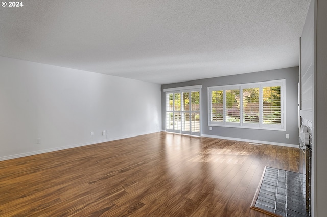 8070 SW Fairway Dr, Wilsonville, OR 97070 - spare room featuring healthy amount of natural light, wood finished floors, a textured ceiling, a fireplace, and baseboards