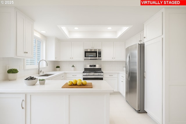 8070 SW Fairway Dr, Wilsonville, OR 97070 - kitchen with stainless steel appliances, a raised ceiling, tasteful backsplash, a peninsula, and light countertops