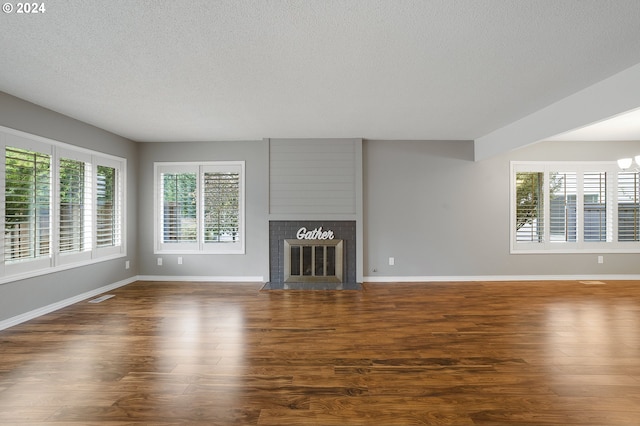 8070 SW Fairway Dr, Wilsonville, OR 97070 - unfurnished living room featuring a textured ceiling, plenty of natural light, a fireplace, baseboards, and wood finished floors
