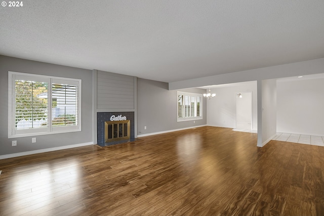 8070 SW Fairway Dr, Wilsonville, OR 97070 - unfurnished living room with a fireplace, a chandelier, baseboards, wood finished floors, and a textured ceiling