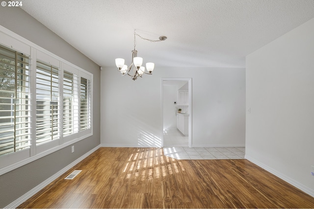 8070 SW Fairway Dr, Wilsonville, OR 97070 - unfurnished room with a chandelier, wood finished floors, baseboards, and a textured ceiling
