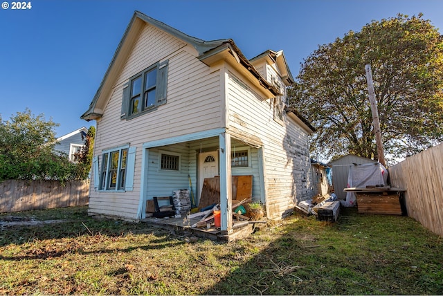 rear view of house featuring a storage shed and a yard