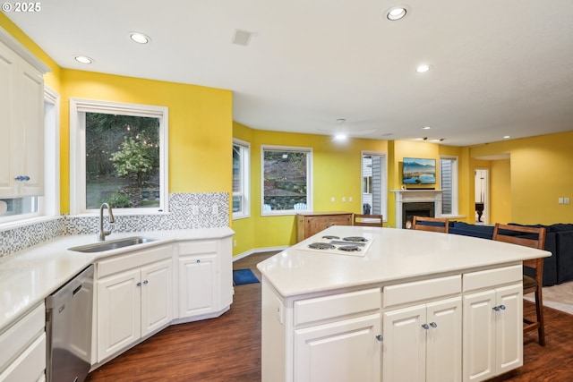kitchen featuring a sink, stainless steel dishwasher, a fireplace, dark wood finished floors, and recessed lighting