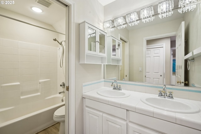 full bathroom featuring toilet, double vanity, and shower / washtub combination