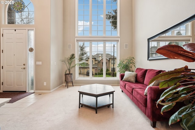 entrance foyer featuring tile patterned flooring, a high ceiling, baseboards, and carpet floors