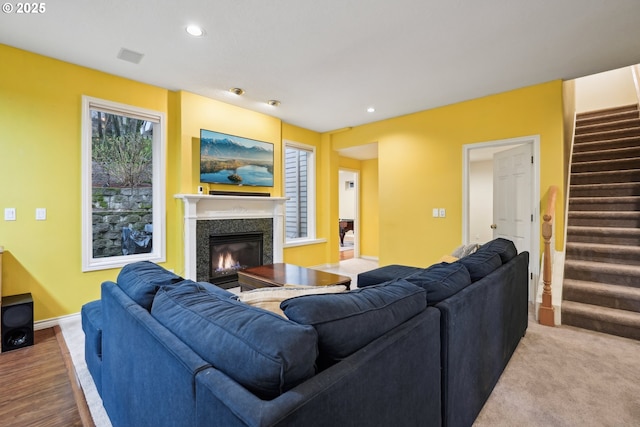 living area with a glass covered fireplace, recessed lighting, stairs, and baseboards