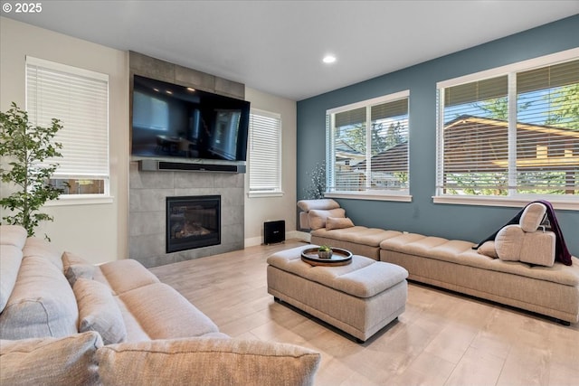 living room with a tile fireplace and light hardwood / wood-style floors