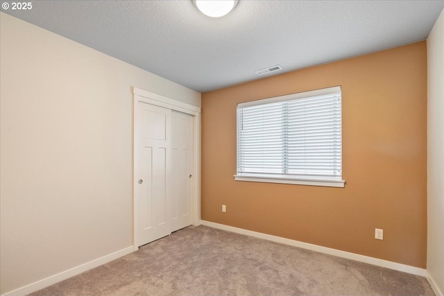 unfurnished bedroom with a closet and light carpet