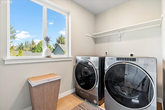 clothes washing area with light wood-type flooring and washing machine and clothes dryer