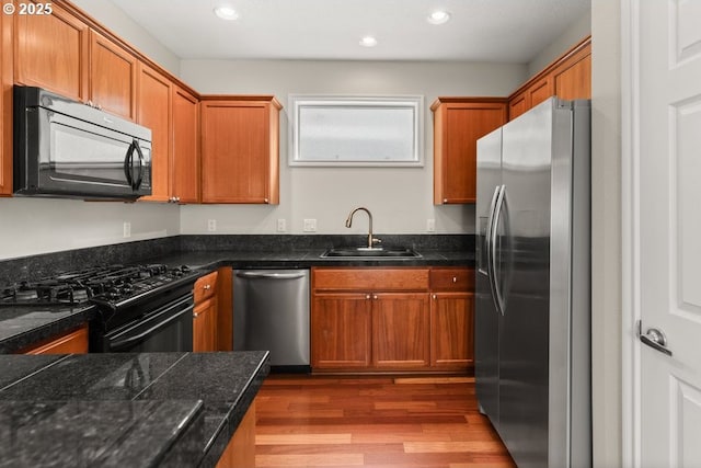 16044 SW Langer Dr, Sherwood, OR 97140 - kitchen featuring black appliances, a sink, wood finished floors, recessed lighting, and brown cabinets