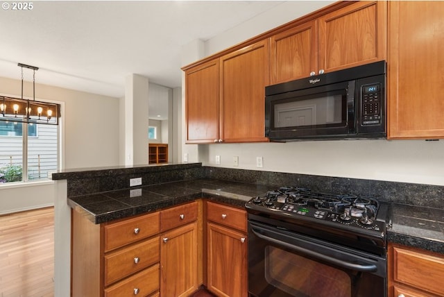 16044 SW Langer Dr, Sherwood, OR 97140 - kitchen with black appliances, tile counters, a peninsula, brown cabinetry, and a chandelier
