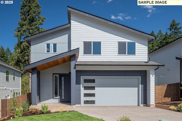 contemporary house with an attached garage, concrete driveway, and fence