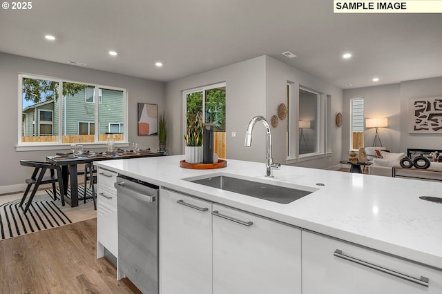 kitchen with a sink, dishwasher, white cabinets, and recessed lighting