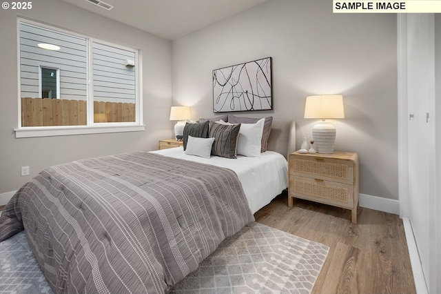 bedroom featuring visible vents, baseboards, and wood finished floors