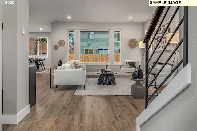 living room featuring a wealth of natural light, baseboards, wood finished floors, and stairs