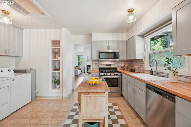 4433 NE 65th Ave, Portland, OR 97218 - kitchen with stainless steel appliances, washing machine and clothes dryer, light flooring, and gray cabinets