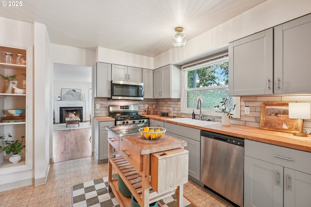 4433 NE 65th Ave, Portland, OR 97218 - kitchen featuring appliances with stainless steel finishes, gray cabinets, wooden counters, and backsplash