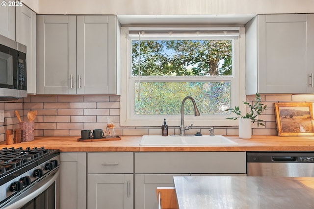4433 NE 65th Ave, Portland, OR 97218 - kitchen featuring appliances with stainless steel finishes, butcher block countertops, and backsplash