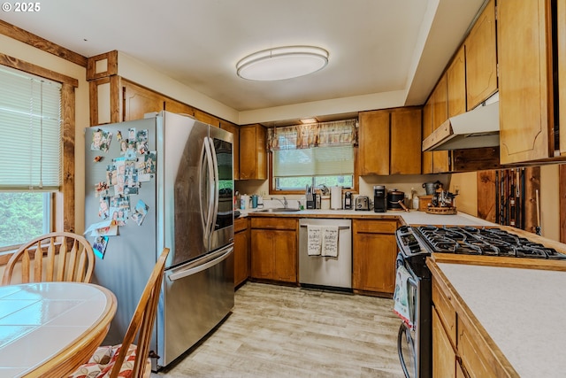 1445 NE 17th St, Gresham, OR 97030 - kitchen with stainless steel appliances, brown cabinets, under cabinet range hood, light countertops, and light wood-style floors