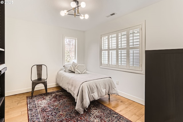 18350 SW Florendo Ln, Beaverton, OR 97007 - bedroom with baseboards, a notable chandelier, visible vents, and hardwood / wood-style floors