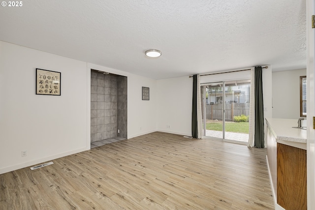 13326 SW Shore Dr, Portland, OR 97223 - unfurnished living room with light wood-type flooring, healthy amount of natural light, and a textured ceiling