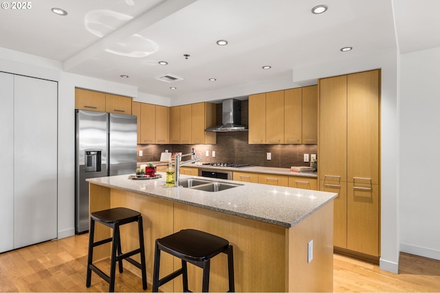 1310 NW Naito Pkwy, Portland, OR 97209 - kitchen with wall chimney exhaust hood, stainless steel appliances, light wood-style floors, backsplash, and a center island with sink