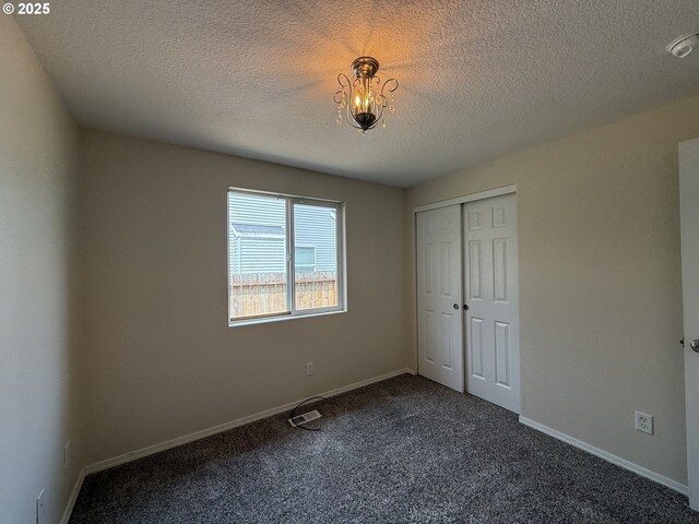 539 NW Blair Loop, Sheridan, OR 97378 - unfurnished bedroom featuring dark carpet, a closet, a chandelier, a textured ceiling, and baseboards