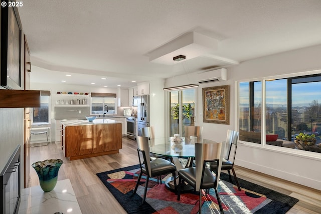 dining area featuring sink, a wealth of natural light, light hardwood / wood-style flooring, and an AC wall unit